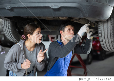 Girl is present while car is being repaired in workshop 141777352