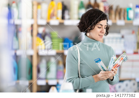 Middle-aged woman choosing toothbrush in retail store Middle-aged woman choosing toothbrush in retail store 141777382