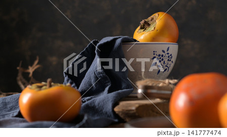 A rustic still life with fresh persimmons and a bowl 141777474