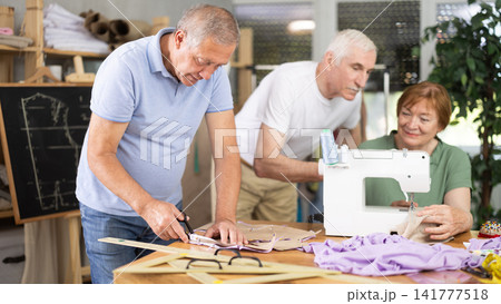 Man cutting fabric along pattern during sewing session for seniors 141777518