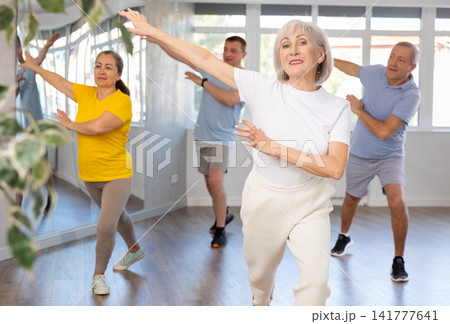 Woman participating in Zumba class for seniors in fitness studio Woman participating in Zumba class for seniors in fitness studio 141777641