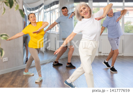 Woman participating in Zumba class for seniors in fitness studio Woman participating in Zumba class for seniors in fitness studio 141777659