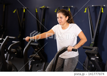 Girl are training on a spin bike simulator. Healthy lifestyle Girl are training on a spin bike simulator. Healthy lifestyle 141777874