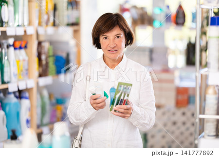 Woman shopper chooses dental kit - toothbrush and toothpaste in supermarket Woman shopper chooses dental kit - toothbrush and toothpaste in supermarket 141777892