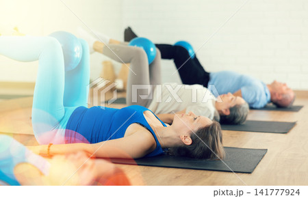 Woman exercising with pilates ball during group training Woman exercising with pilates ball during group training 141777924