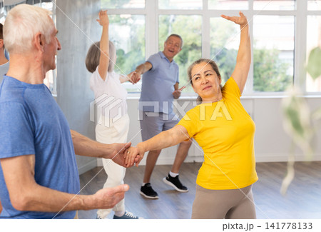 Mature men and wome learn energetic twist dance in choreography studio Mature men and wome learn energetic twist dance in choreography studio 141778133