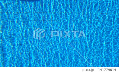 Rippled blue pool water surface reveals tiled floor pattern with sunlight caustic reflections 141779014