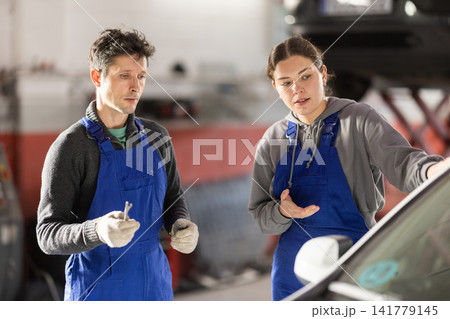 Girl and man auto mechanics talk about algorithm of work, consult with each other Girl and man auto mechanics talk about algorithm of work, consult with each other 141779145