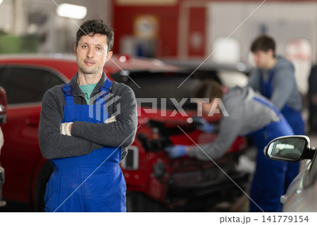 Portrait of a positive girl auto mechanic in the interior of car service 141779154