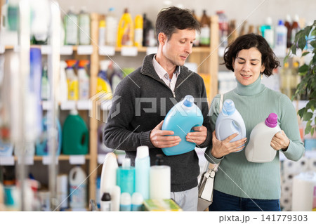 Married couple chooses detergent in household goods department of supermarket Married couple chooses detergent in household goods department of supermarket 141779303