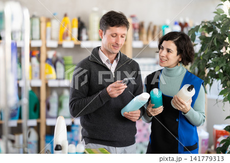 Female salesperson offers to buy shampoo or shower gel while man checks QR code using smartphone 141779313