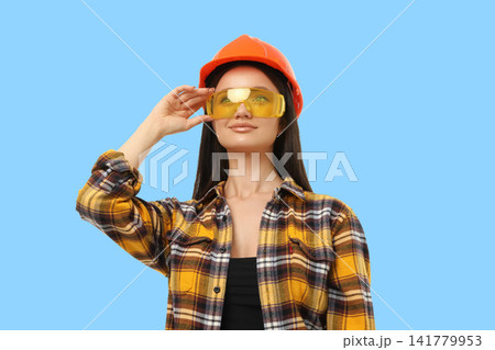 A woman in safety gear poses against a blue background 141779953