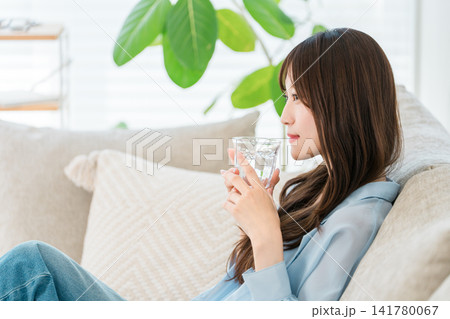 リビングのソファに座り水,白湯を飲む若いアジア人女性 リビングのソファに座り水,白湯を飲む若いアジア人女性 141780067