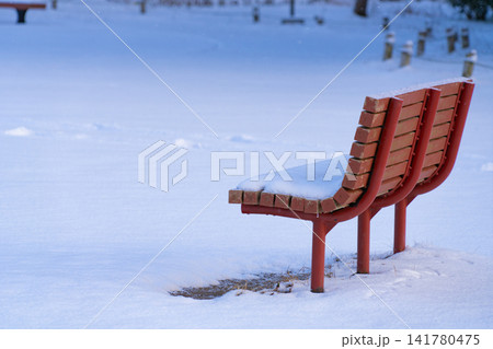 雪に覆われた静かな冬の公園の赤いベンチ 141780475