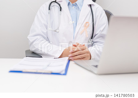 doctor using laptop and report notes on notebook. peach ribbon concept of September Uterine Cancer Awareness month, Endometrial, Gynecologic, Uterus and Ovaries, Endometriosis, June Vaginal cancer doctor using laptop and report notes on notebook. peach ribbon concept of September Uterine Cancer Awareness month, Endometrial, Gynecologic, Uterus and Ovaries, Endometriosis, June Vaginal cancer 141780503