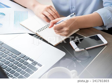 Person using calculator with notebook laptop and phone on desk 141781803