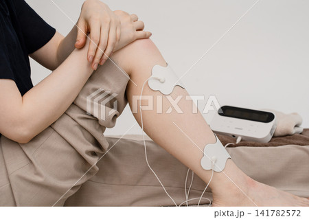 脚の電極パッドに触れる女性の低周波セルフケア 脚の電極パッドに触れる女性の低周波セルフケア 141782572