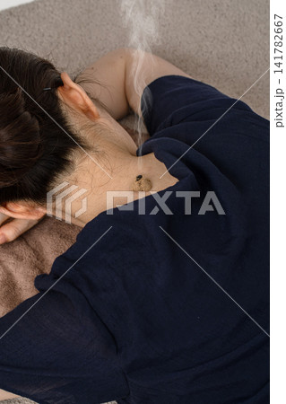 うつ伏せの女性のうなじから煙が立つもぐさ灸 うつ伏せの女性のうなじから煙が立つもぐさ灸 141782667