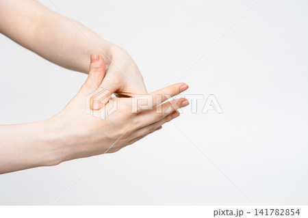 手の甲を親指で押してほぐす女性の手元 141782854