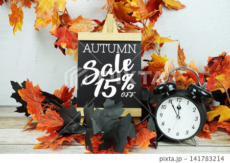 Autumn Sale 15% text with alarm clock and maple leaf decoration on wooden background Autumn Sale 15% text with alarm clock and maple leaf decoration on wooden background 141783214