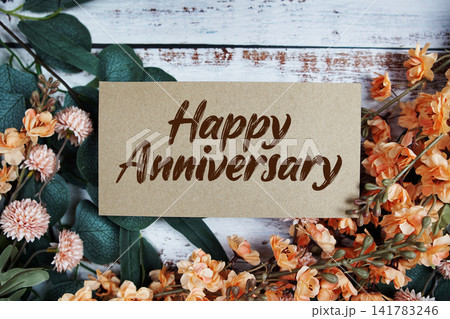 Happy Anniversary text with flowers decorations on wooden background Happy Anniversary text with flowers decorations on wooden background 141783246