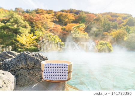 紅葉広がる露天風呂の湯縁に置かれた湯桶と手ぬぐい( 紅葉広がる露天風呂の湯縁に置かれた湯桶と手ぬぐい( 141783380