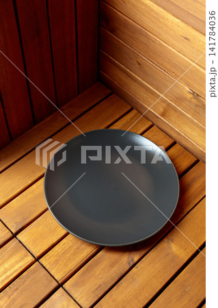 Empty black plate on natural wooden background. 141784036