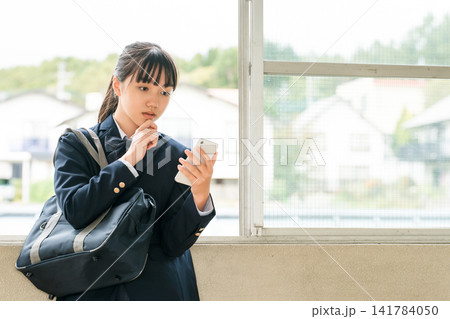 校舎の廊下でスマホを使う小学生,中学生,高校生の女の子(考える,悩む,迷う,困る) 校舎の廊下でスマホを使う小学生,中学生,高校生の女の子(考える,悩む,迷う,困る) 141784050