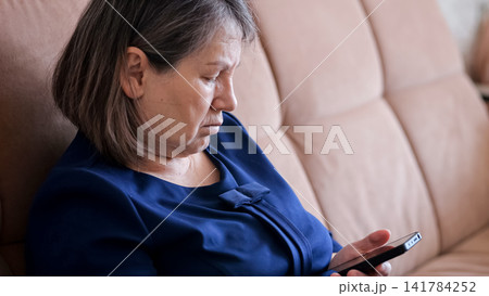 Senior woman on a sofa focused on her smartphone, learning and connecting through digital appsconfidently embracing technology, communication and modern digital literacy at home Senior woman on a sofa focused on her smartphone, learning and connecting through digital appsconfidently embracing technology, communication and modern digital literacy at home 141784252