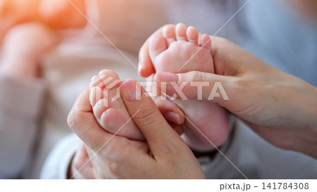 Mother gently holding baby feet symbolizing new life Mother gently holding baby feet symbolizing new life 141784308