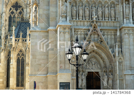 Ornate neogothic facade with statues and lantern at Votivkirche church Ornate neogothic facade with statues and lantern at Votivkirche church 141784368