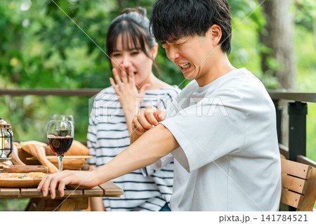 アウトドアで食事中に虫刺されで困っているカップル 141784521