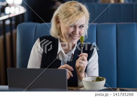 White Consultant Smiling With Salad Fork, Playful Expression In Cozy Cafe Booth With Laptop Nearby, Savoring Fresh Greens And Relaxed Lunch Mood, Mindful Eating And Wellness Focus During Productive 141785266