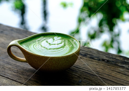 Serene Morning Cup of Matcha Latte with Leaf Art on Wooden Table Serene Morning Cup of Matcha Latte with Leaf Art on Wooden Table 141785377