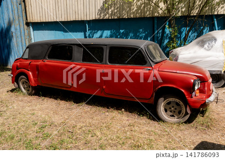 Unique Custom Red Limousine Car Parked on Dry Grass Outdoors Unique Custom Red Limousine Car Parked on Dry Grass Outdoors 141786093