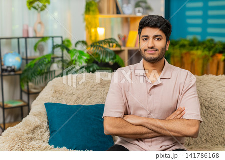 Indian man on home sofa changing serious face into smile for strong portrait video at home indoors Indian man on home sofa changing serious face into smile for strong portrait video at home indoors 141786168