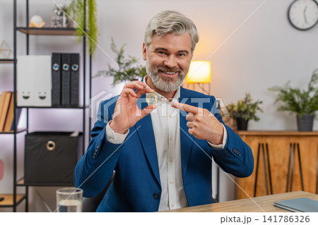 Middle-aged businessman holds golden bitcoin coin to camera explaining investment potential optimism Middle-aged businessman holds golden bitcoin coin to camera explaining investment potential optimism 141786326