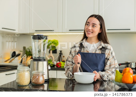 Young woman whisking batter in kitchen preparing simple breakfast recipe for healthy eating habits 141786373