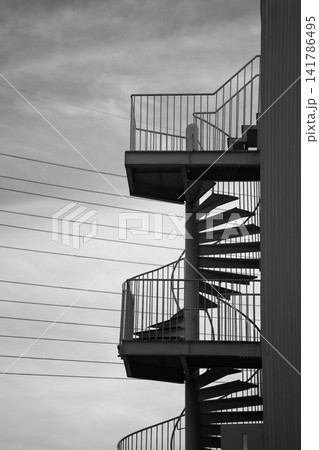 曇り空を背景にした屋外の金属製らせん階段のモノクロ写真 曇り空を背景にした屋外の金属製らせん階段のモノクロ写真 141786495