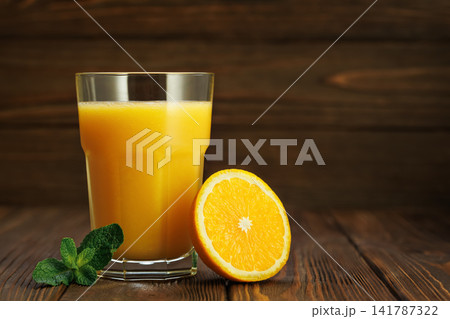 Orange juice in glass with mint and half citrus fruit on rustic wooden table Orange juice in glass with mint and half citrus fruit on rustic wooden table 141787322