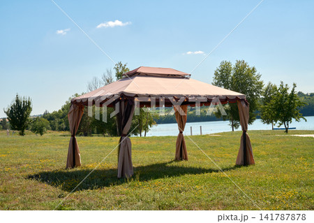 An elegant outdoor gazebo by a scenic lake in a sunny summer landscape. An elegant outdoor gazebo by a scenic lake in a sunny summer landscape. 141787878
