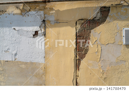 Peeling Paint On Old Yellow Wall With Exposed Brick, Metal Vent And Cracked Plaster Texture Peeling Paint On Old Yellow Wall With Exposed Brick, Metal Vent And Cracked Plaster Texture 141788470