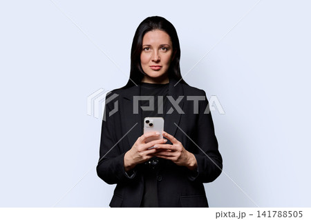 Business woman holding smartphone and looking directly at camera 141788505