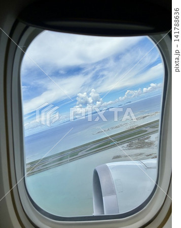 飛行機の窓から眺めるエメラルドグリーンの海と滑走路 141788636