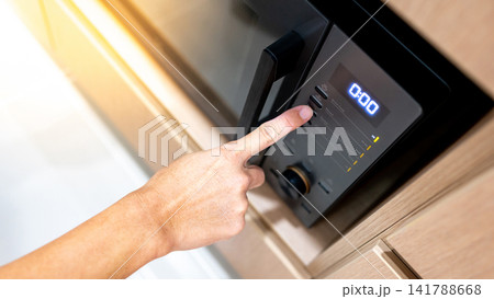 Hand pressing button setting mode and timer on microwave oven Hand pressing button setting mode and timer on microwave oven 141788668