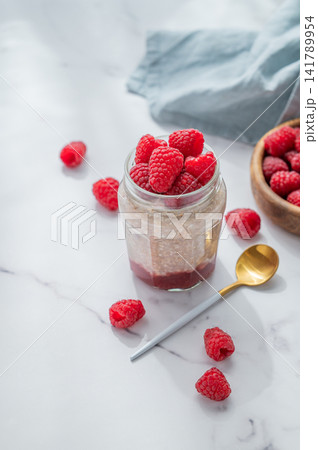 Oatmeal in a jar with raspberries overnight in alternative milk on a light background 141789954