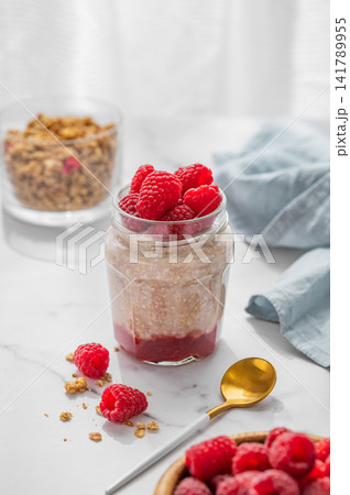 Oatmeal in a jar with raspberries overnight in alternative milk on a light background 141789955