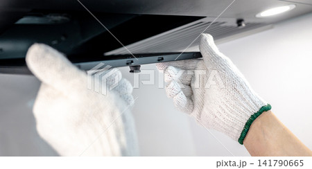 Male hand technician removing range hood filter from modern cooker hood 141790665