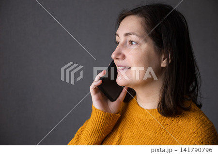 Pregnant woman talking on a smartphone in a studio with soft light and a calm expression Pregnant woman talking on a smartphone in a studio with soft light and a calm expression 141790796