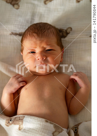 Newborn baby frowning with curious expression on blanket Newborn baby frowning with curious expression on blanket 141790844